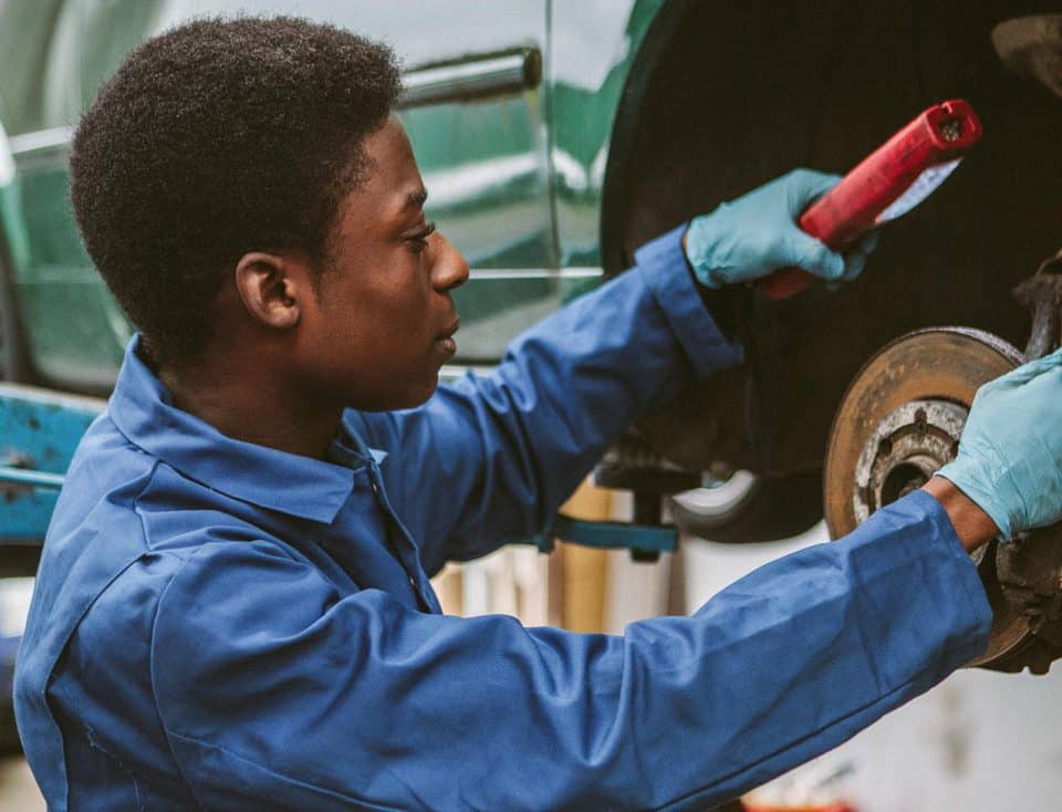 auto-werkstatt-gruen Mechanikerin schraubt an Auto in Werkstatt